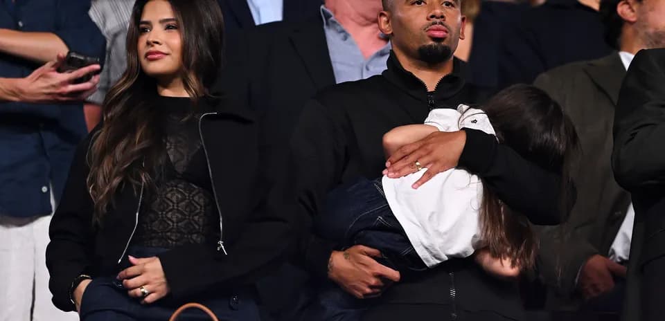 Couple with child at an event, spectators in background