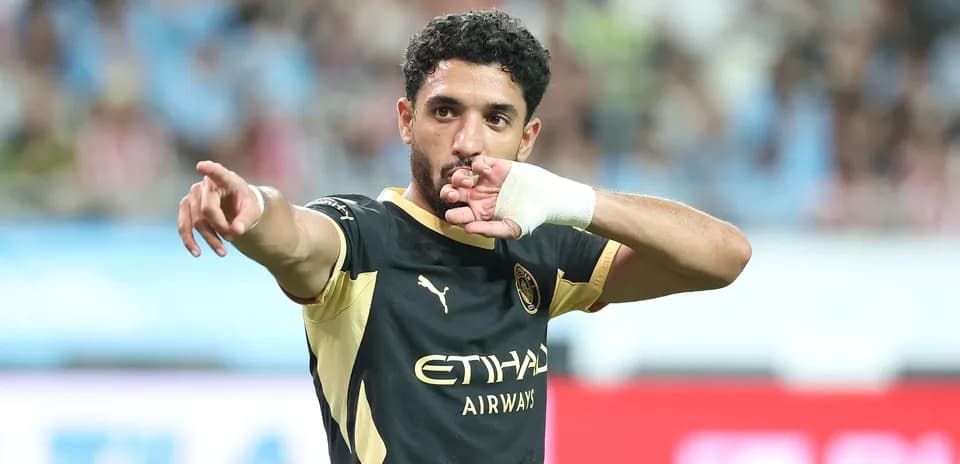 Futbolchi maydonda qo'lini ko'tarib ko'rsatmoqda