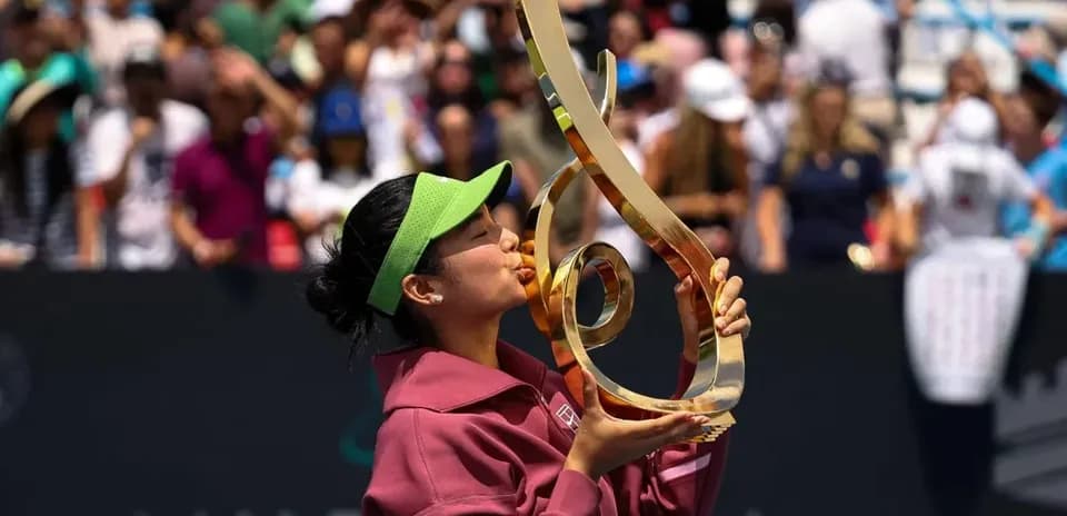 Tennis player kissing trophy on court