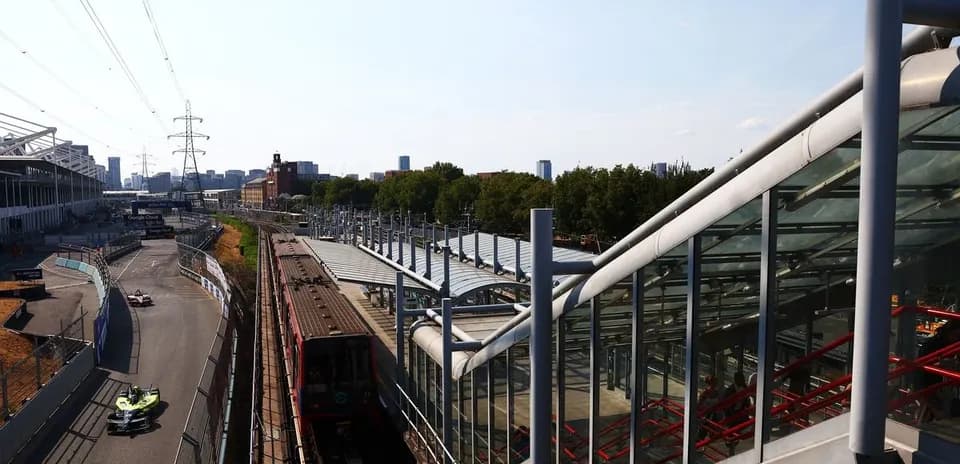 Formula E car racing near railway station and skyline