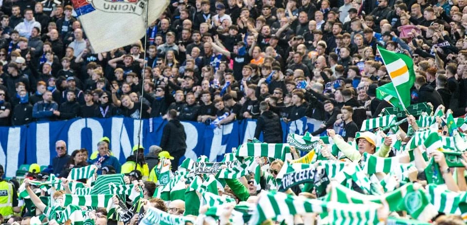 Celtic fans waving scarves in stadium stands