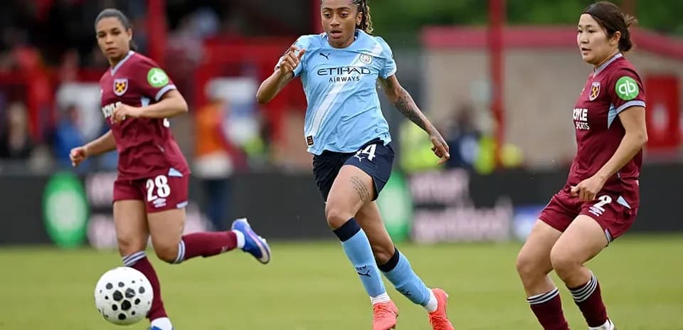 Manchester City player dribbling past West Ham opponents