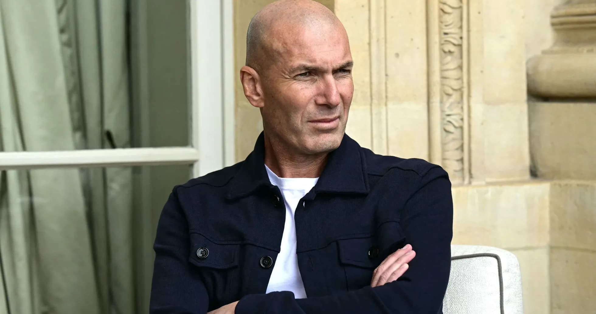 Bald man sitting with arms crossed outdoors
