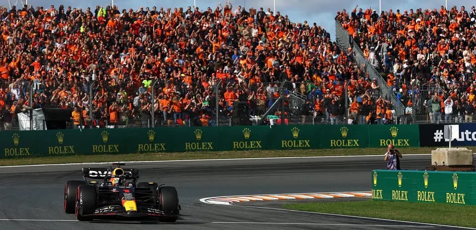 Formula 1 car racing past cheering crowd at event