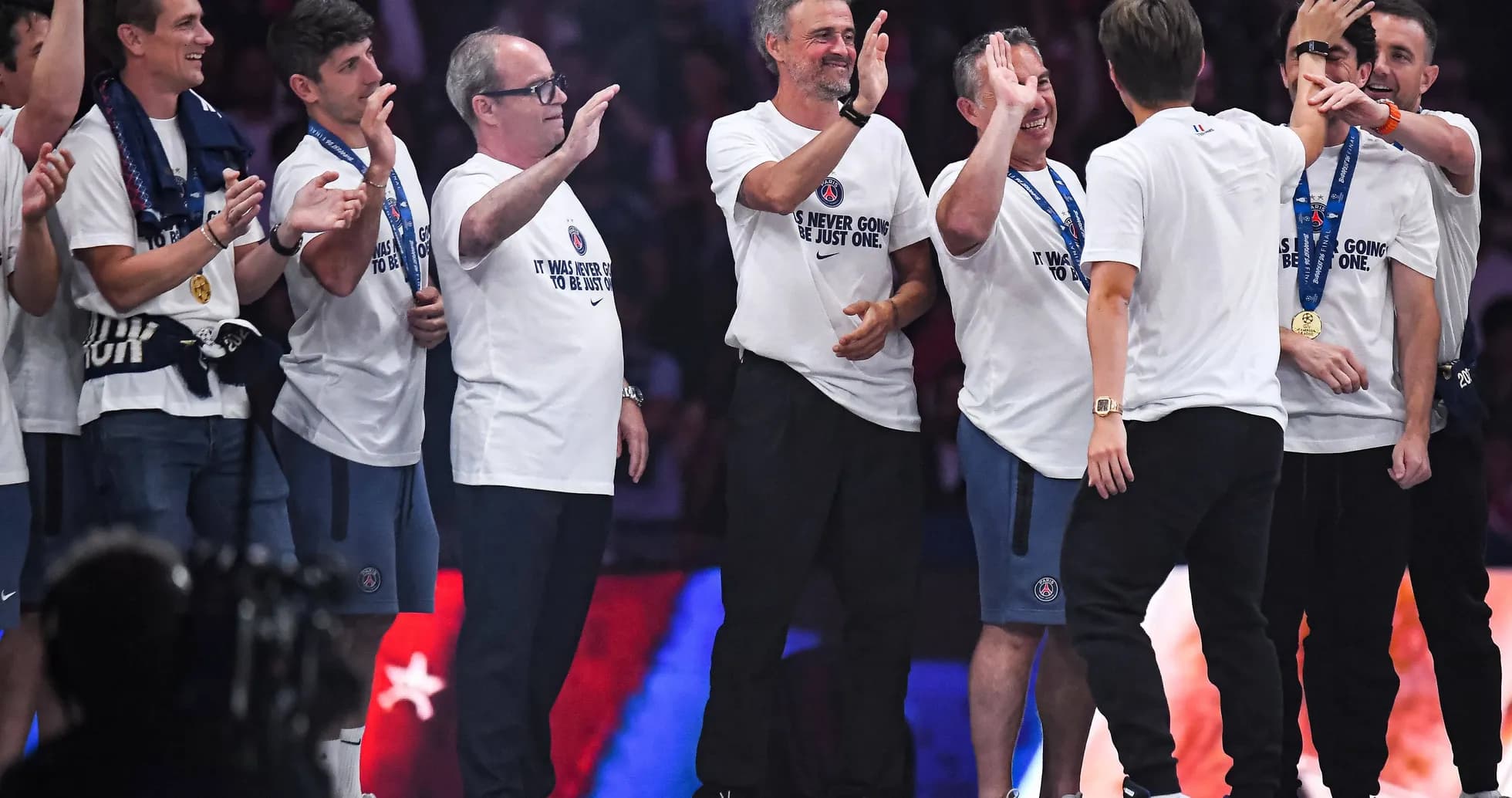 Coaches and staff celebrating with medals on stage