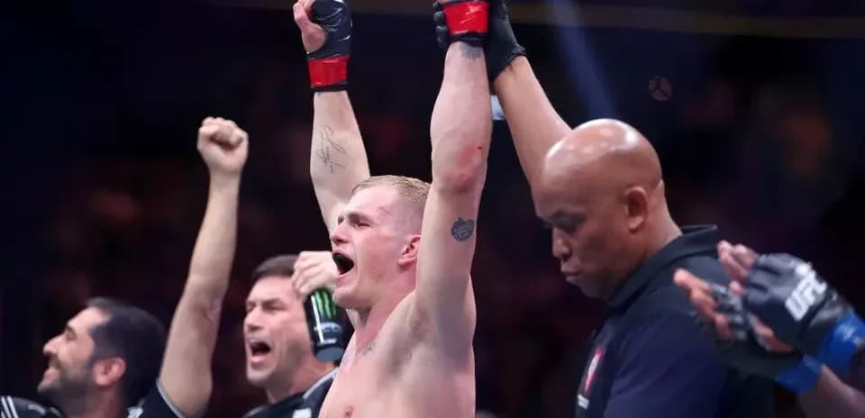 Fighter celebrating victory with raised hands in octagon