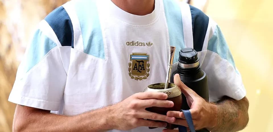 Futbolchi Argentina formasini kiyingan, ichimlik ushlab turibdi