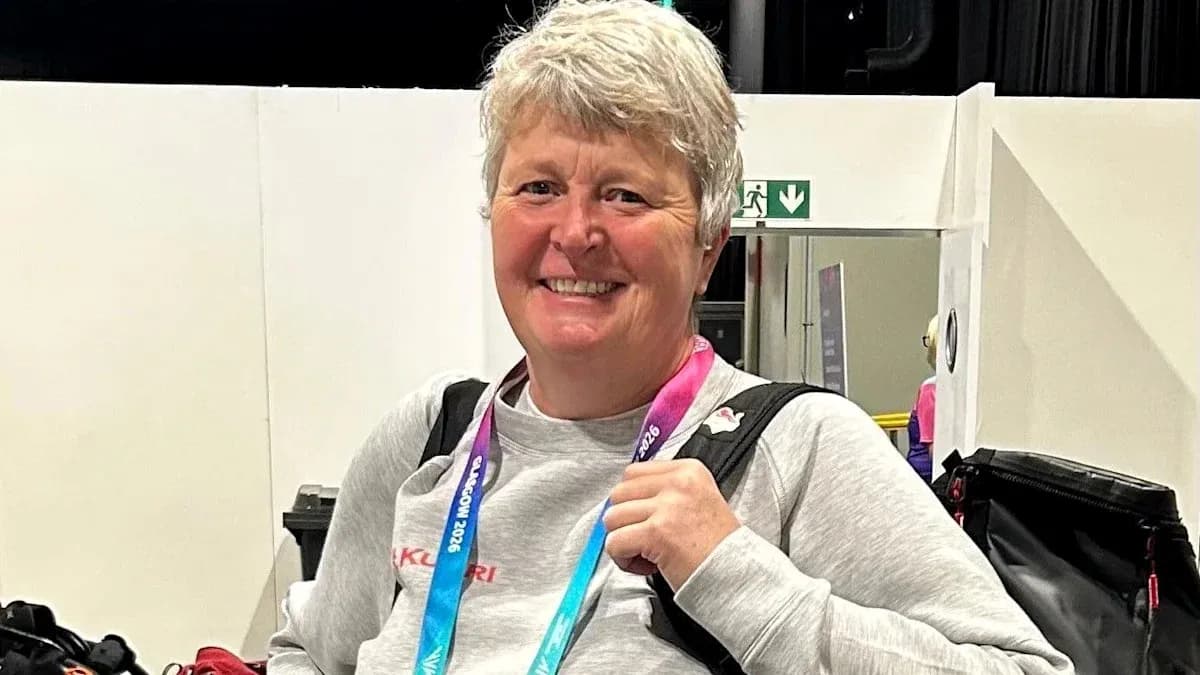 Coach smiling with medal and backpack in venue Coach smiling with medal and backpack in venue