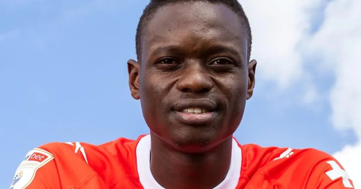 Futbolchi qizil forma kiyib, kamera tomonga qarab turibdi Futbolchi qizil forma kiyib, kamera tomonga qarab turibdi