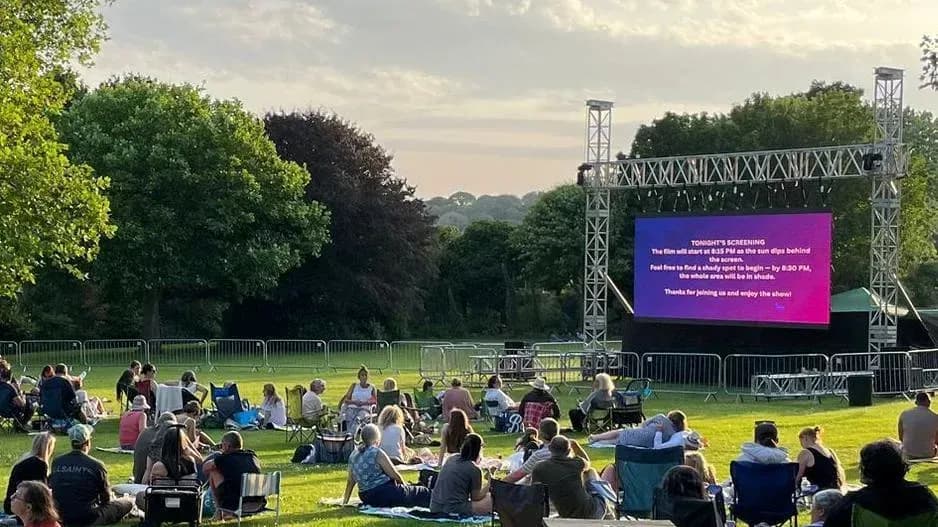 People watching an outdoor movie screening in park People watching an outdoor movie screening in park