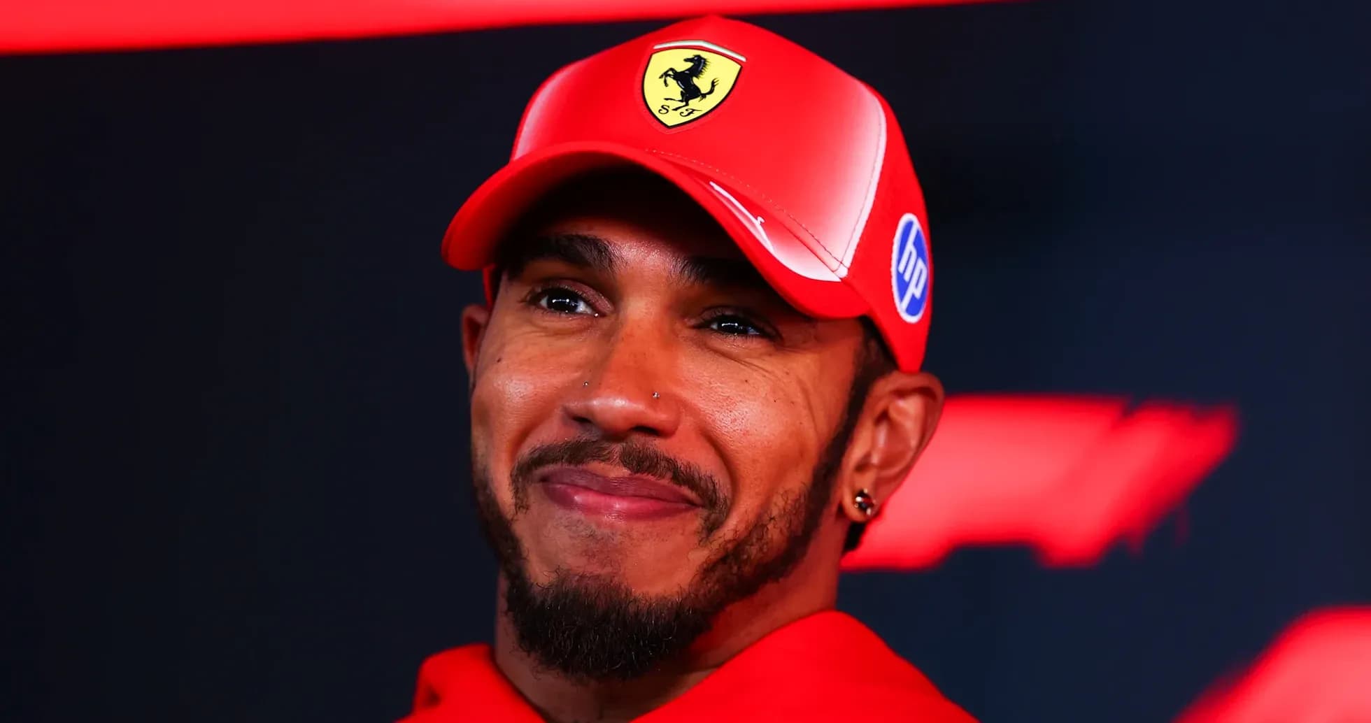 Lewis Hamilton smiling in red Ferrari cap Lewis Hamilton smiling in red Ferrari cap