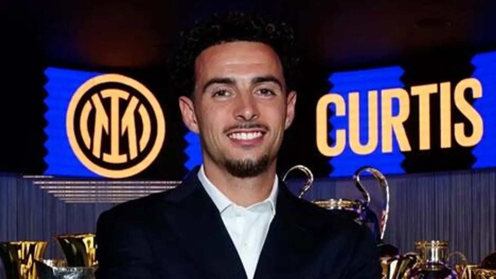 Futbolchi mukofotlar oldida turib kulmoqda Futbolchi mukofotlar oldida turib kulmoqda
