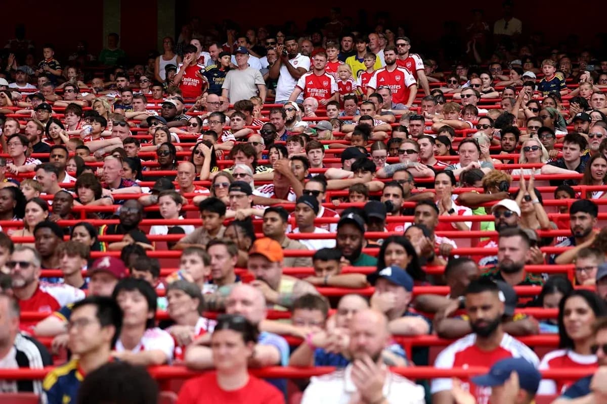 Arsenal fans seated in stadium stands during match Arsenal fans seated in stadium stands during match
