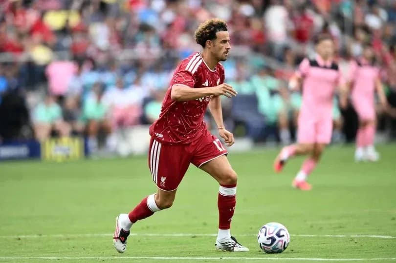 Futbolchi Liverpool formasida to'pni haydashda Futbolchi Liverpool formasida to'pni haydashda