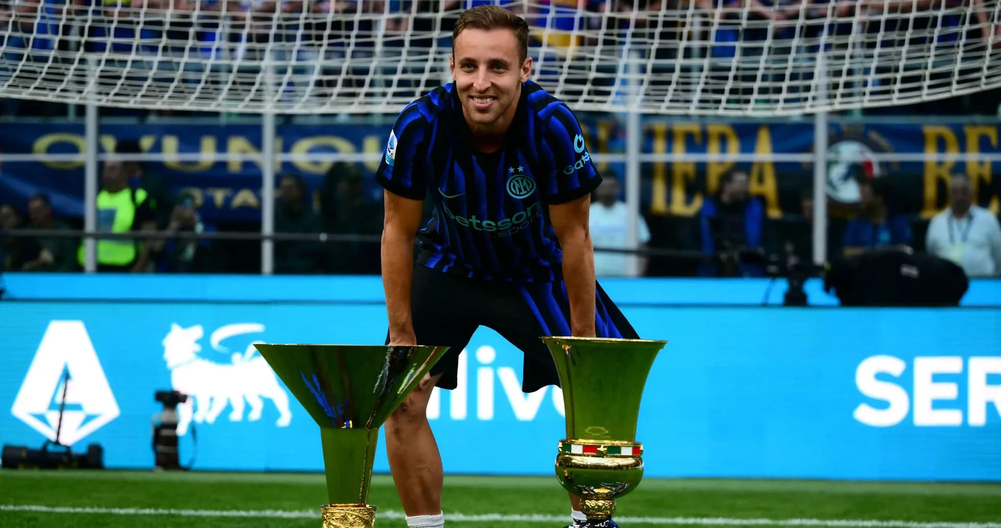 Futbolchi ikki kubok bilan maydonda tabassum qilmoqda Futbolchi ikki kubok bilan maydonda tabassum qilmoqda