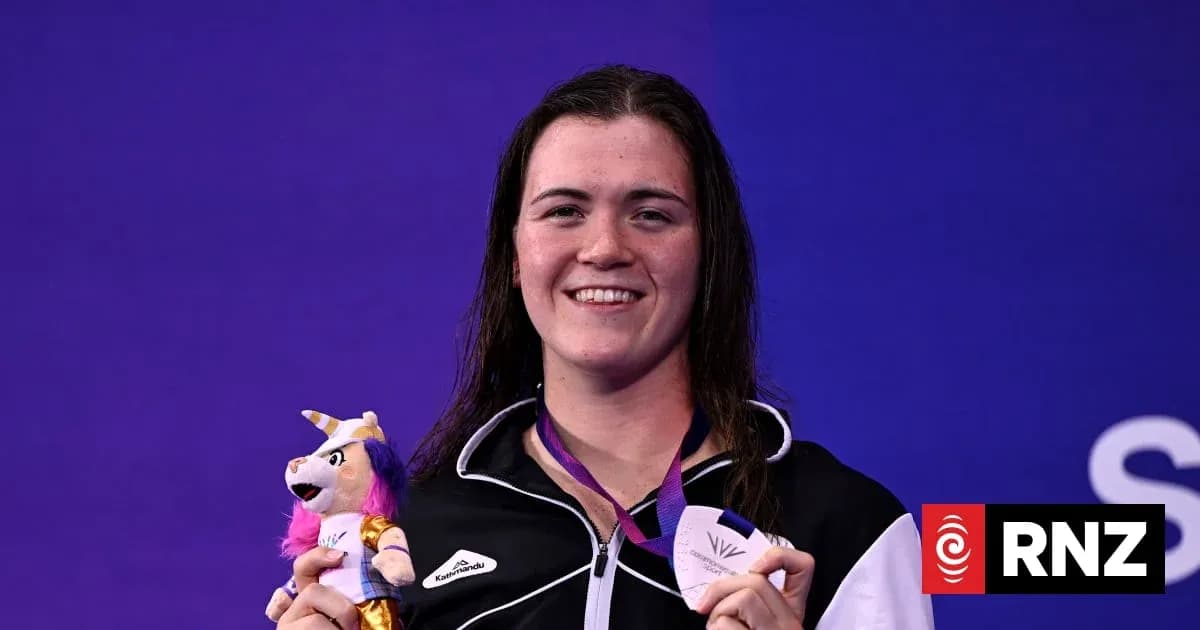 Athlete holding medal and plush toy at event Athlete holding medal and plush toy at event