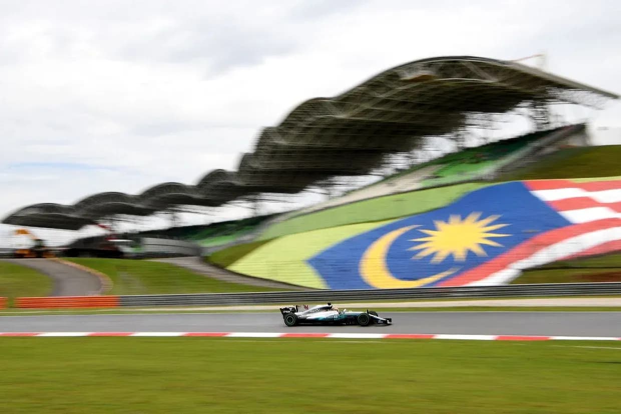 Formula 1 car racing at Malaysian circuit with flag Formula 1 car racing at Malaysian circuit with flag