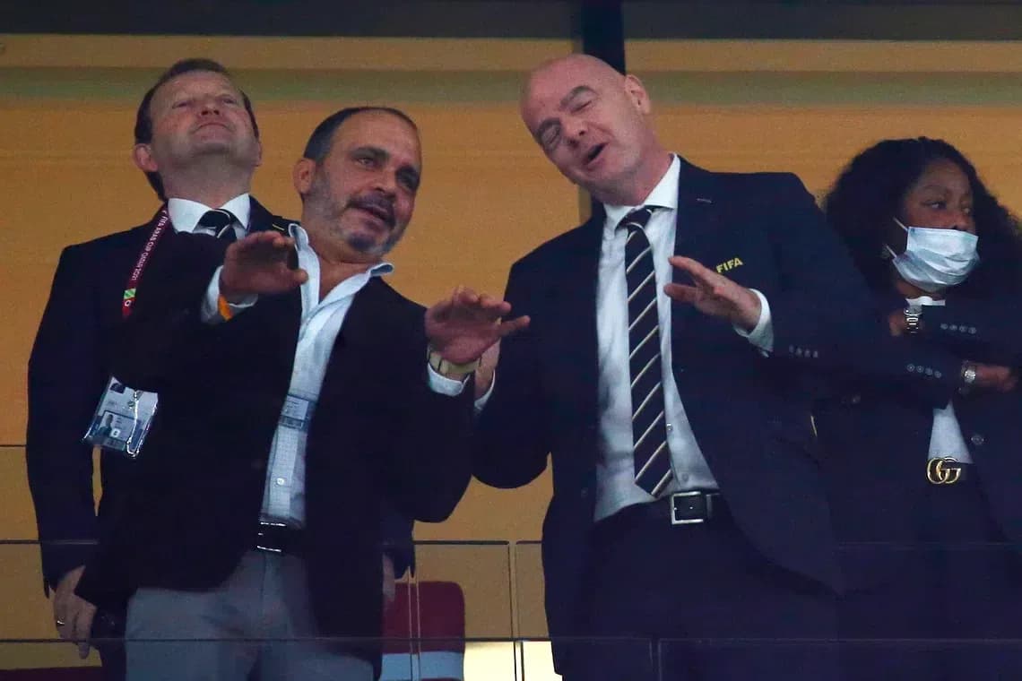 Two men in suits conversing in a stadium box Two men in suits conversing in a stadium box
