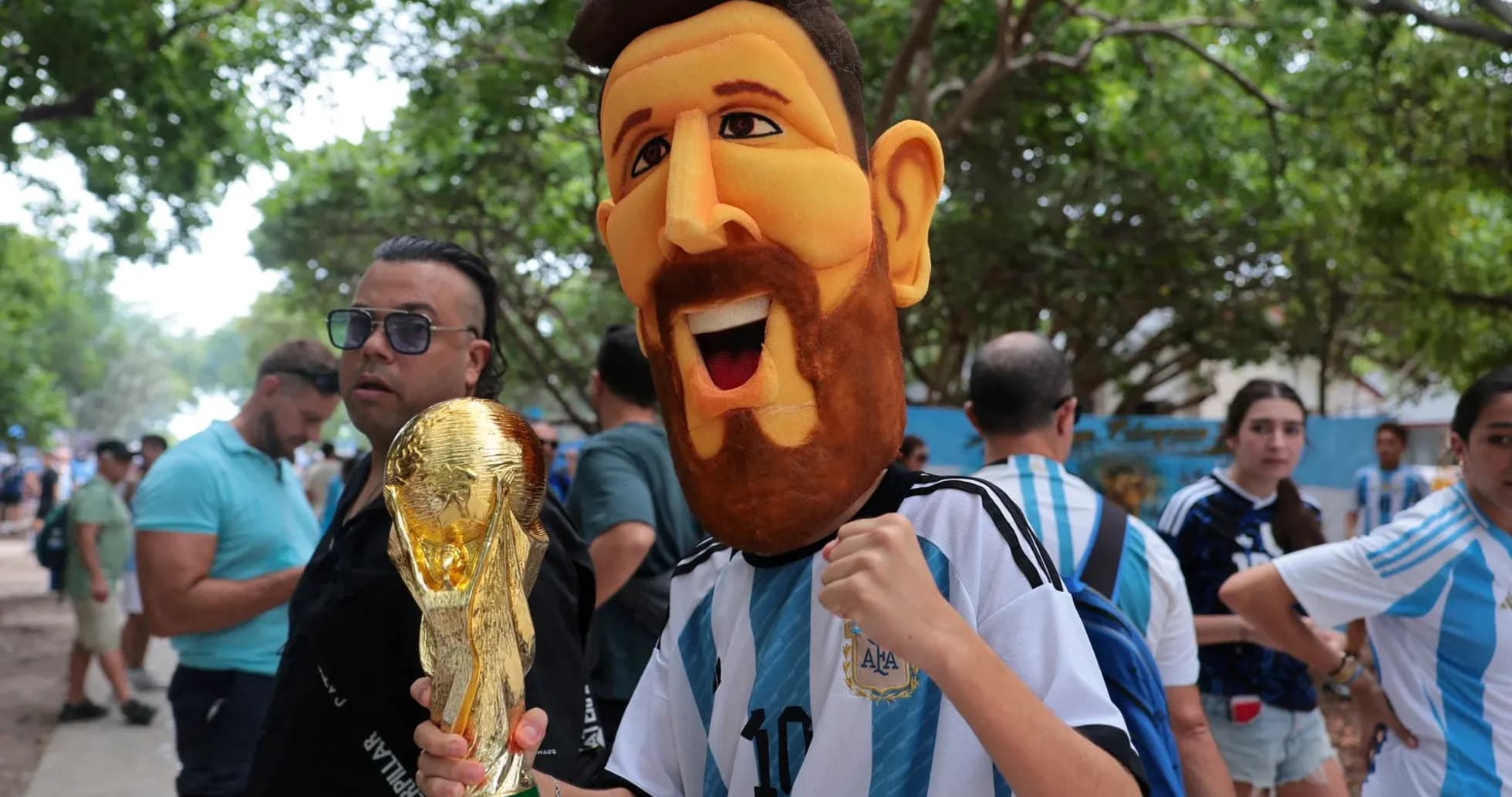 Fan wearing Messi mask holding World Cup trophy Fan wearing Messi mask holding World Cup trophy