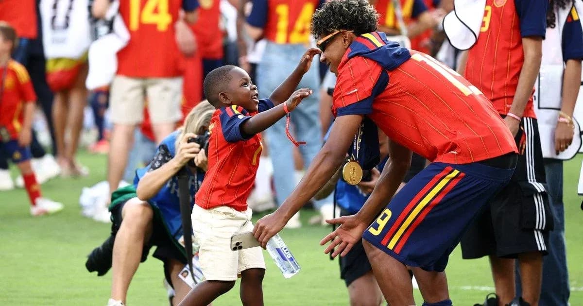 Bola o'ynayotgan bola futbolchiga quchilib turibdi Bola o'ynayotgan bola futbolchiga quchilib turibdi