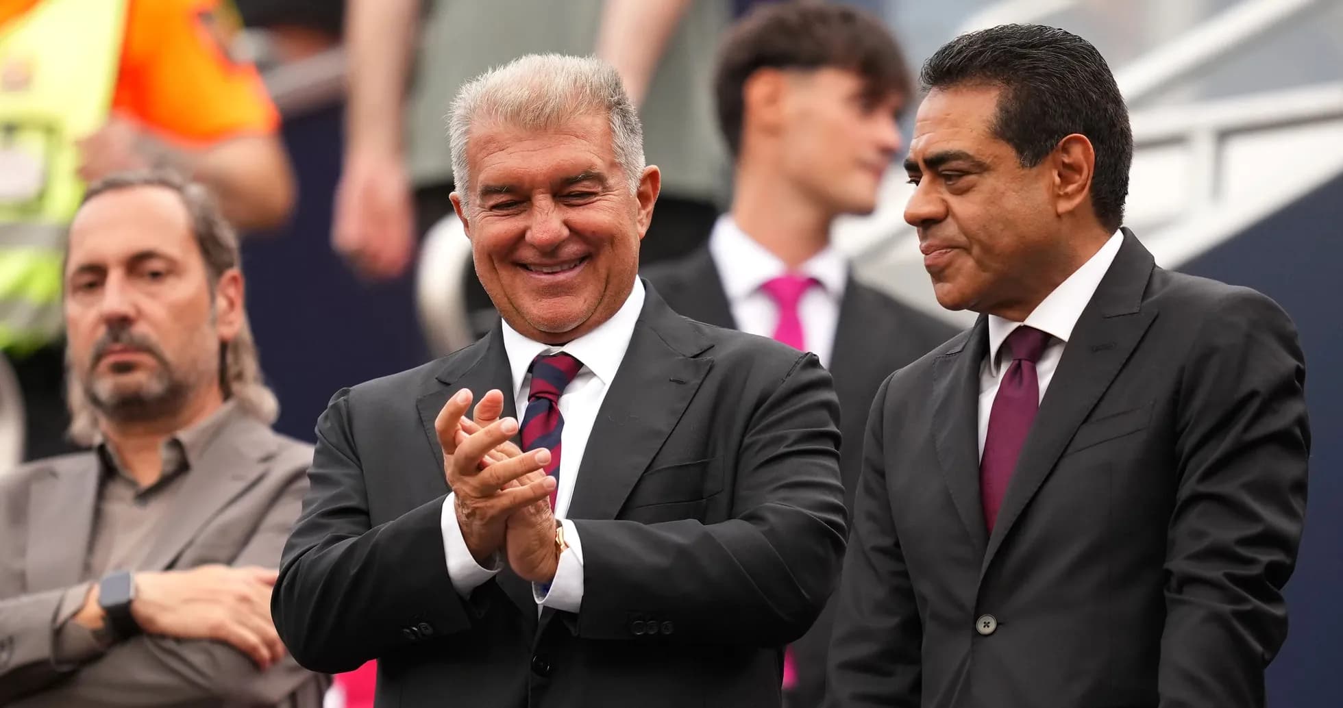 Three men in suits at a sporting event Three men in suits at a sporting event