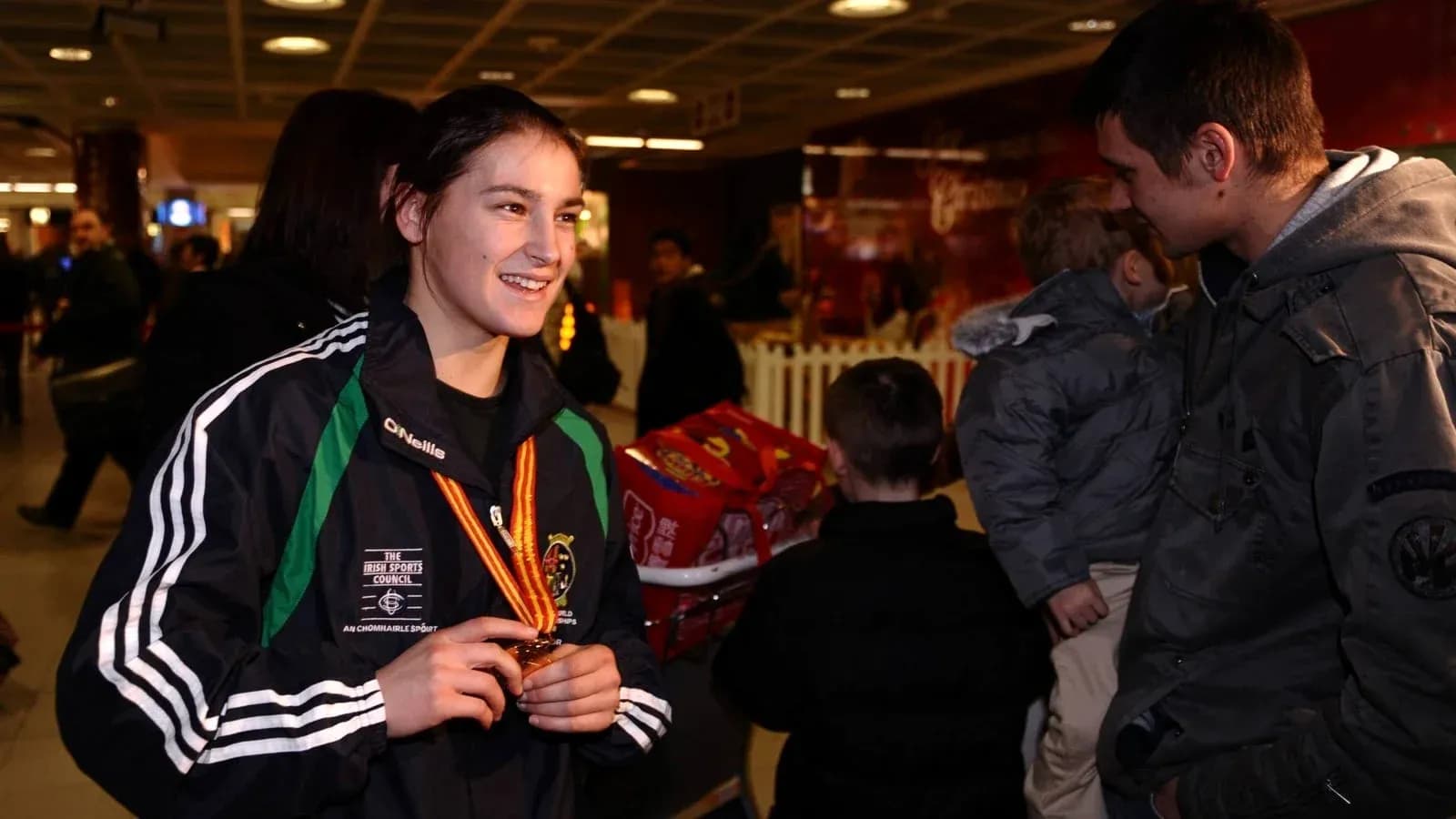 Athlete displaying medal at airport with fans Athlete displaying medal at airport with fans