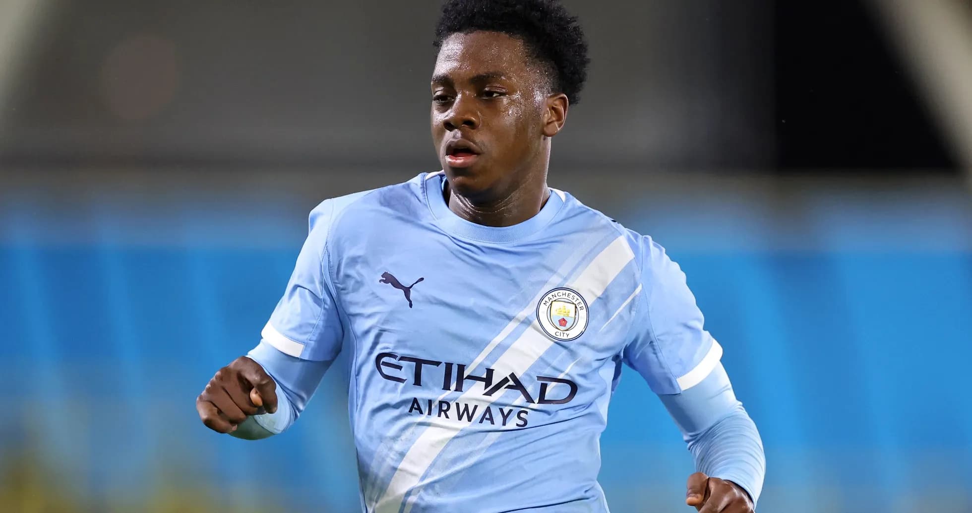 Futbolchi Manchester City formasida yugurmoqda Futbolchi Manchester City formasida yugurmoqda