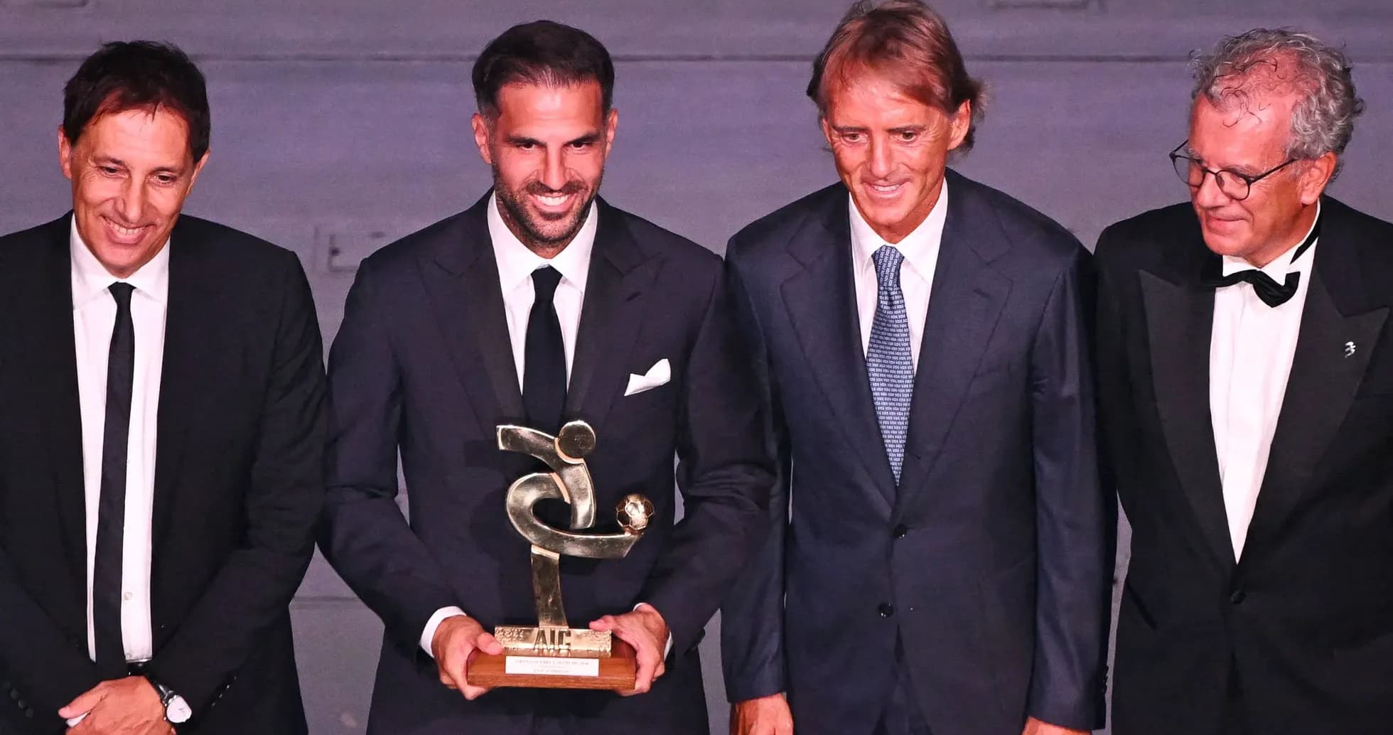 Four men at award ceremony holding trophy Four men at award ceremony holding trophy