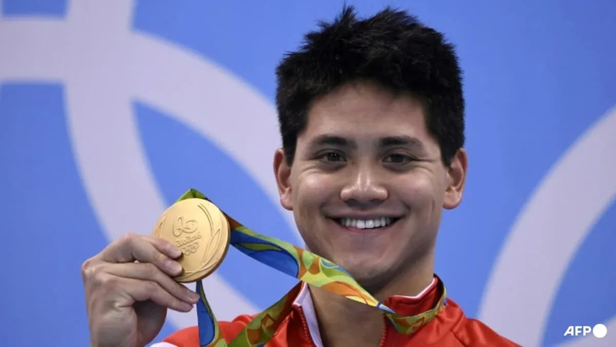 Sportchi oltin medalni ko'tarib turib tabassum qilmoqda Sportchi oltin medalni ko'tarib turib tabassum qilmoqda