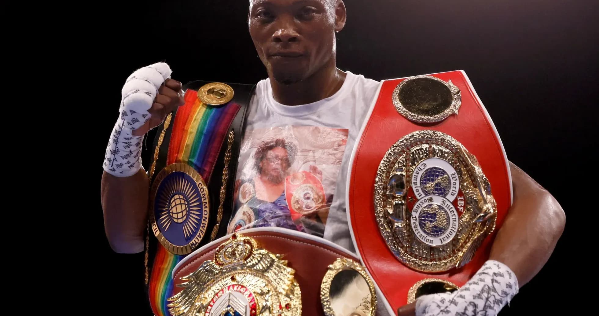 Boxer holding multiple championship belts in ring Boxer holding multiple championship belts in ring