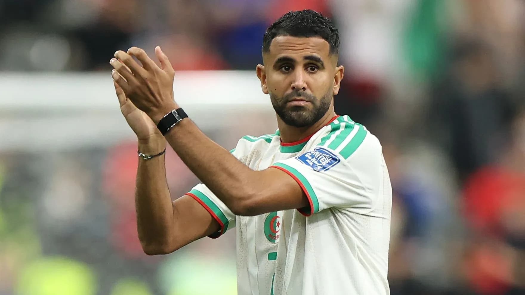 Futbolchi sahna oldida qo'llarini ko'tarib turgan Futbolchi sahna oldida qo'llarini ko'tarib turgan