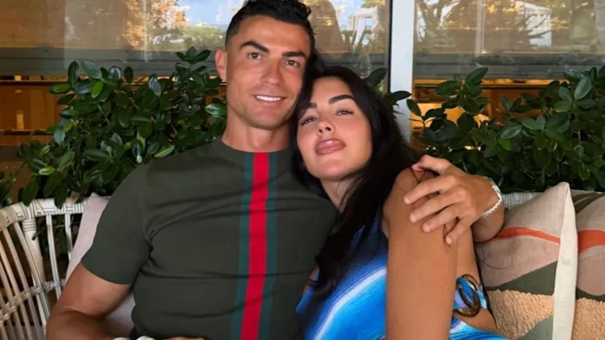 Couple posing together on a couch surrounded by plants Couple posing together on a couch surrounded by plants