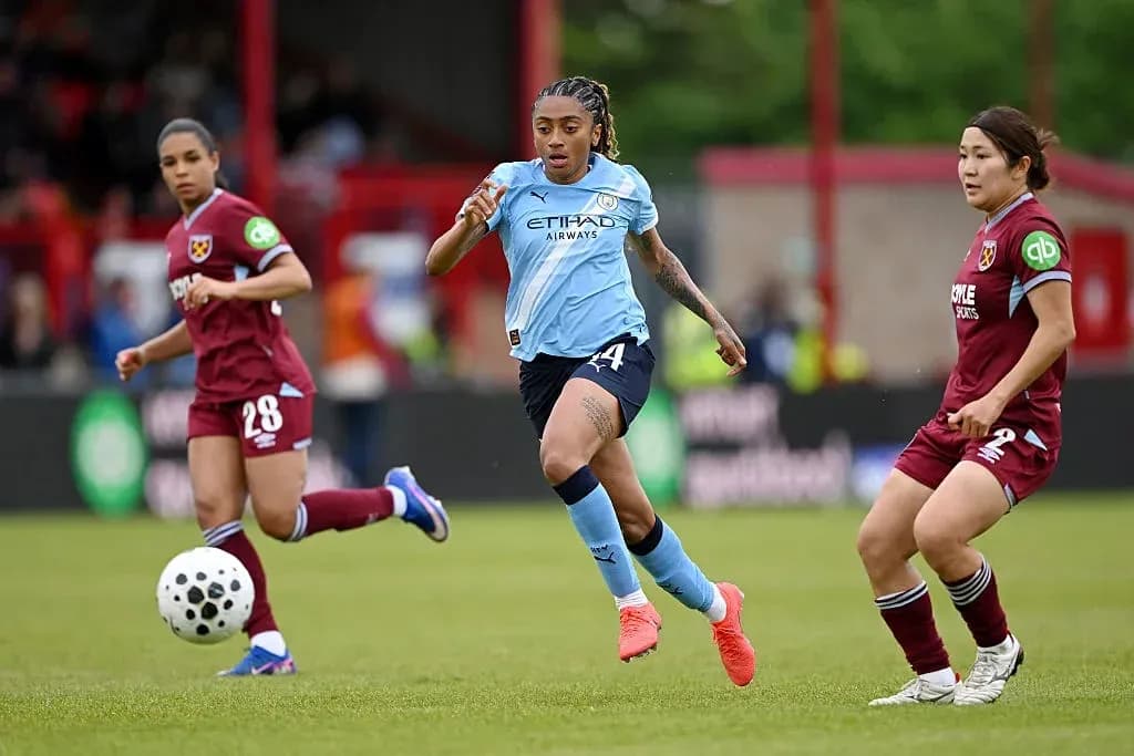 Manchester City player dribbling past West Ham opponents Manchester City player dribbling past West Ham opponents