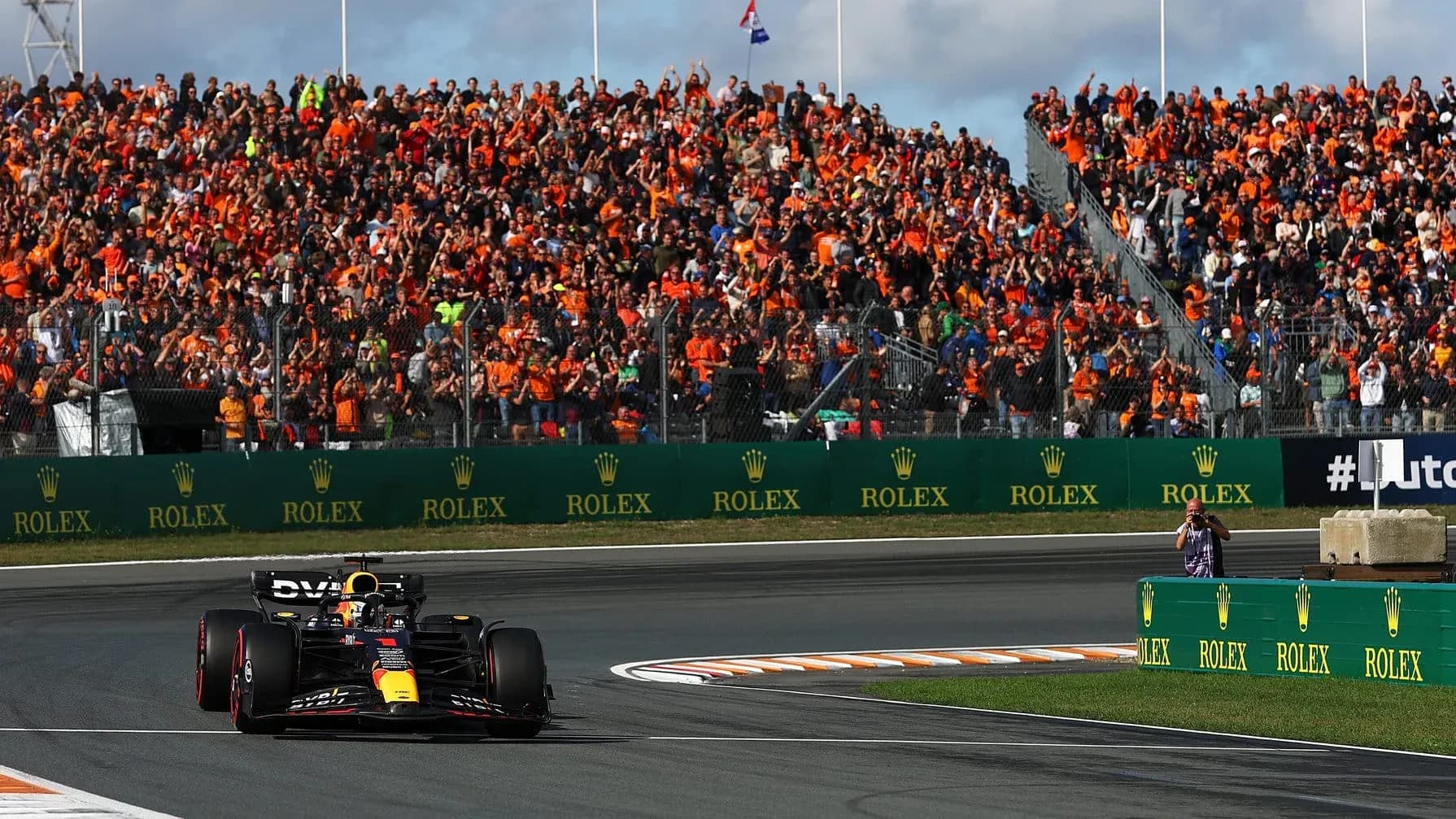 Formula 1 car racing past cheering crowd at event Formula 1 car racing past cheering crowd at event