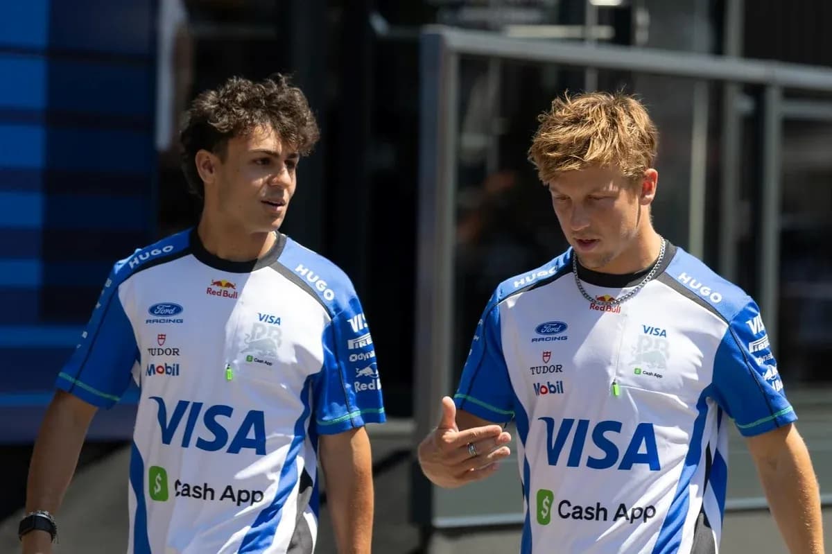 Two drivers in team uniforms walking and talking Two drivers in team uniforms walking and talking